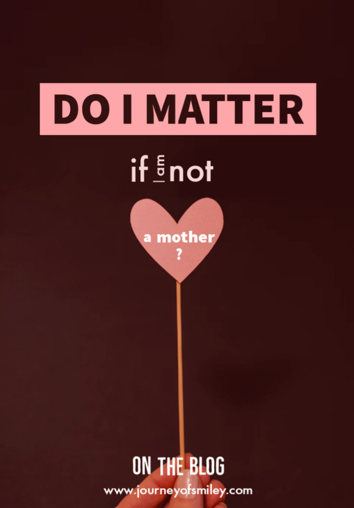 Do I matter if I am not a mother on a dark background, a heart on a stick holding in a hand