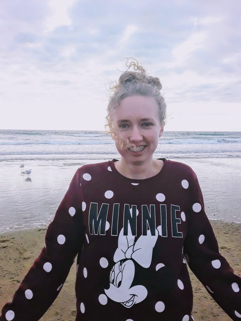A lady standing in front of the sea at the seaside, trauma survivor, trauma healing journey on Journeyofsmiley blog