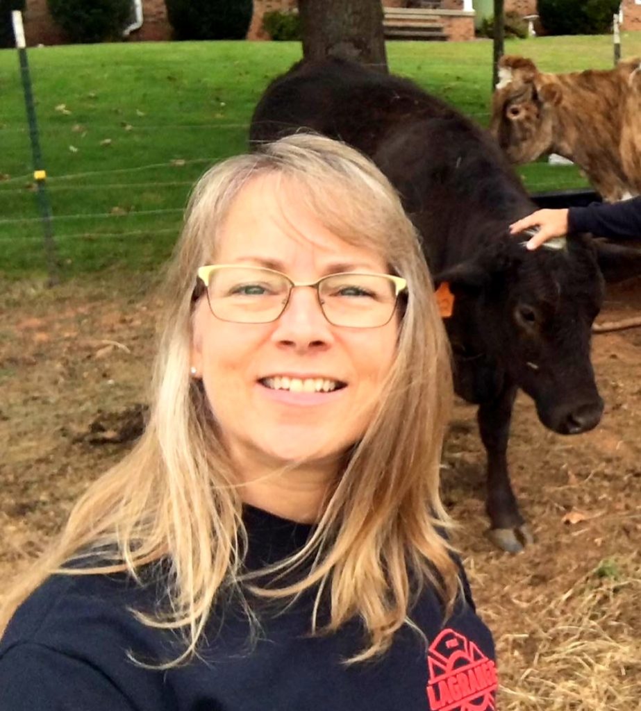 A photo of a woman with two cows behind her 