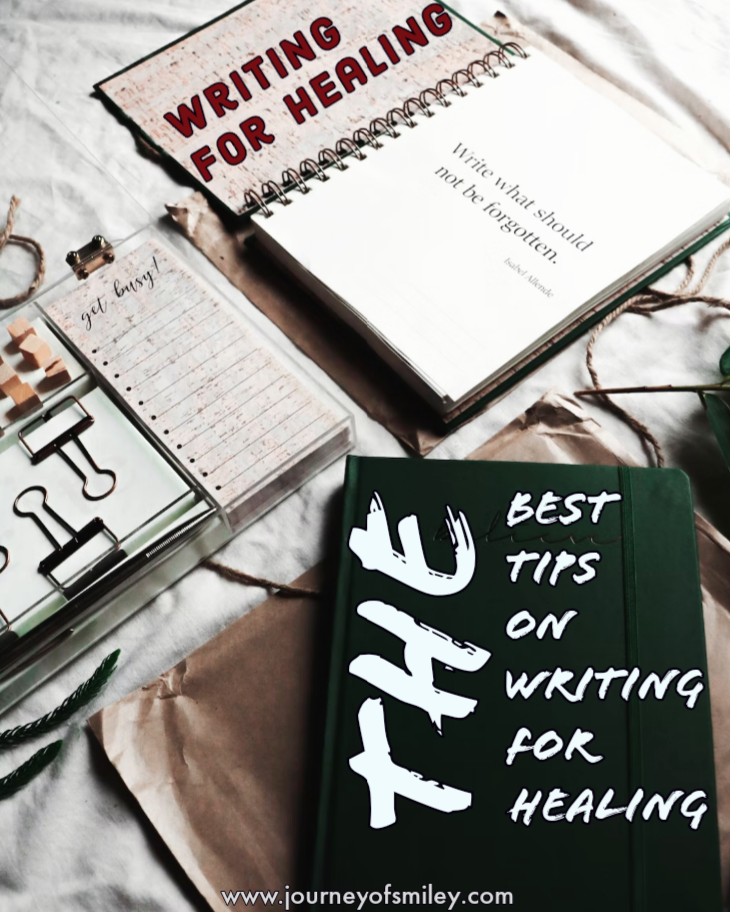 Three books on a bed, one of them open and on the cover of the book is written Writing for healing. A closed book next to it with the title Best tips on writing for healing on Journeyofsmiley blog