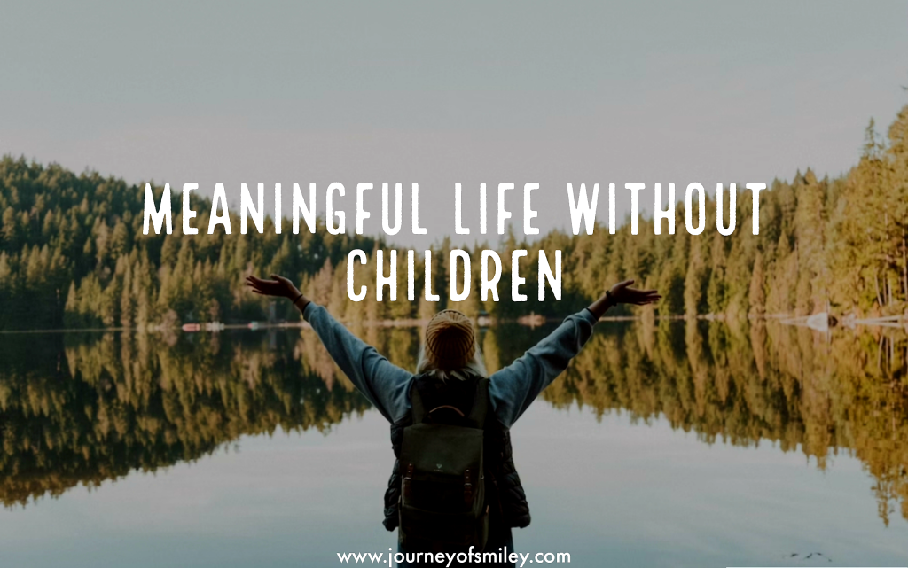 A woman in the nature, lake ahead of her, trees in the background, woman standing with her hands up towards the sky and the title is Meaningful life without children on Journeyofsmiley blog