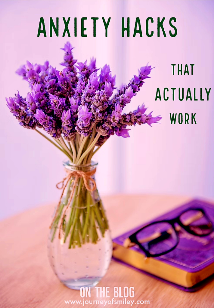 A vase with purple lavender flowers in it, a book with a purple cover and glasses on it next to the vase and the title is Anxiety Hacks that actually work on Journeyofsmiley blog