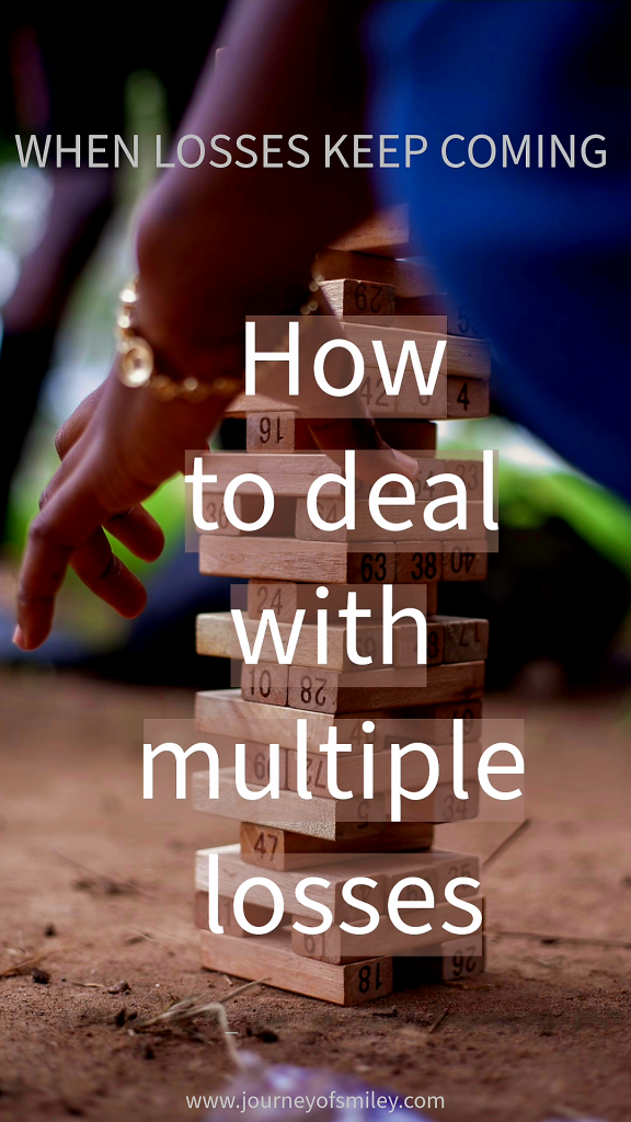 A Jenga game, wooden blocks piled on each other, and a hand trying to move a block, and above it is the title When Losses Keep Coming, How to deal with multiple losses, on Journeyofsmiley blog. 